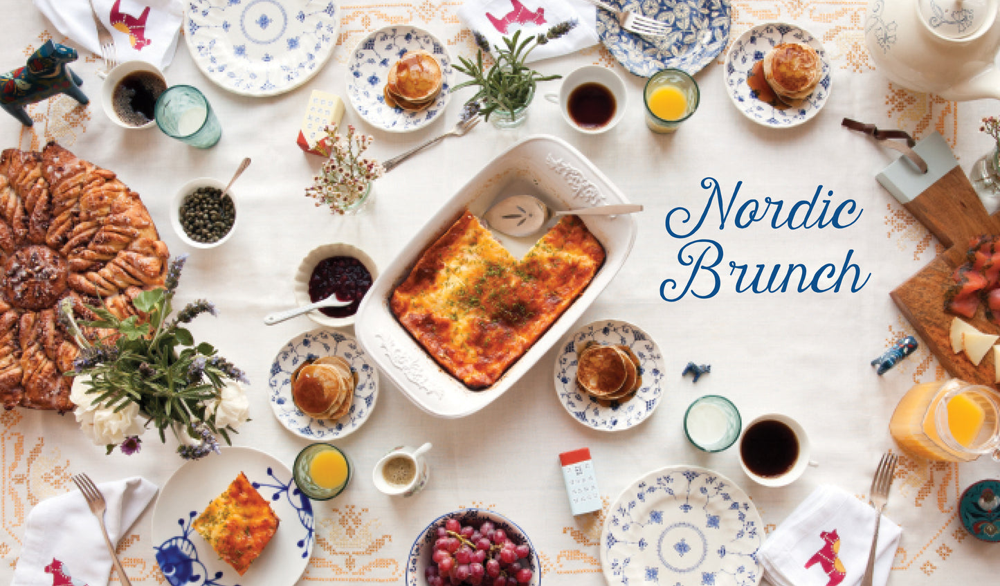 From the book 'Scandinavian Gatherings' Nordic Brunch spread with various dishes and drinks on a white tablecloth.