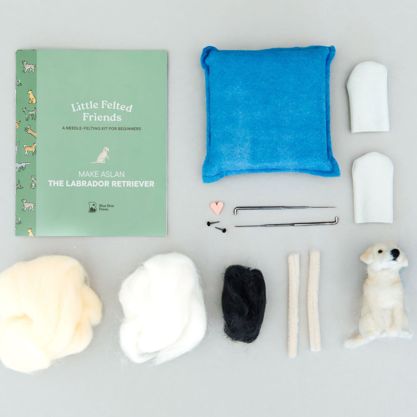 Collection of dog-related items including a book, plush toys, and tools on a gray background