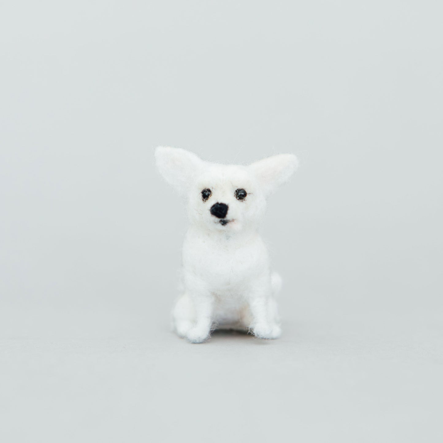 Small white dog figurine on a light gray background