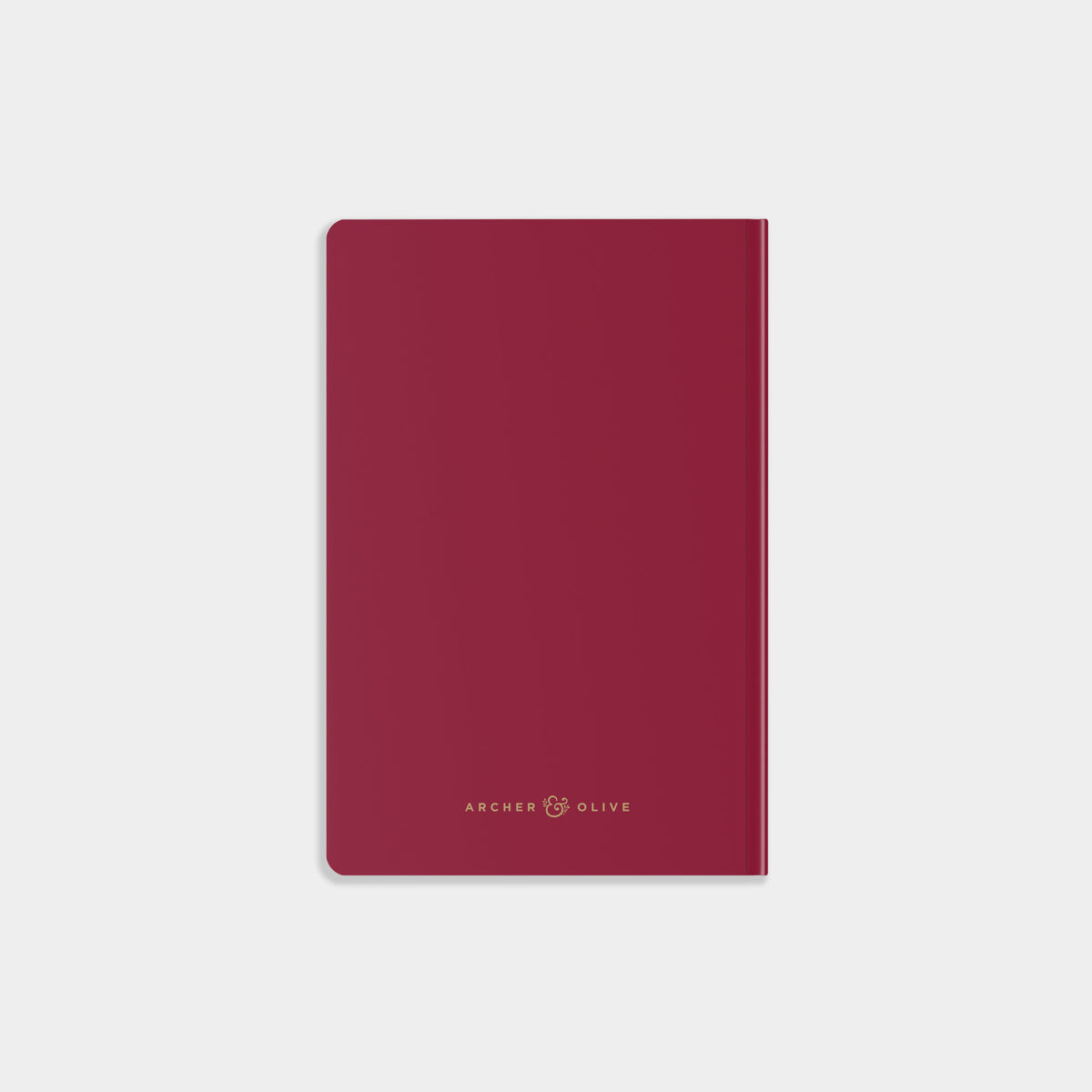 A slim, minimalist notebook with a deep burgundy cover and gold foil branding at the bottom, displayed on a clean, light gray background.