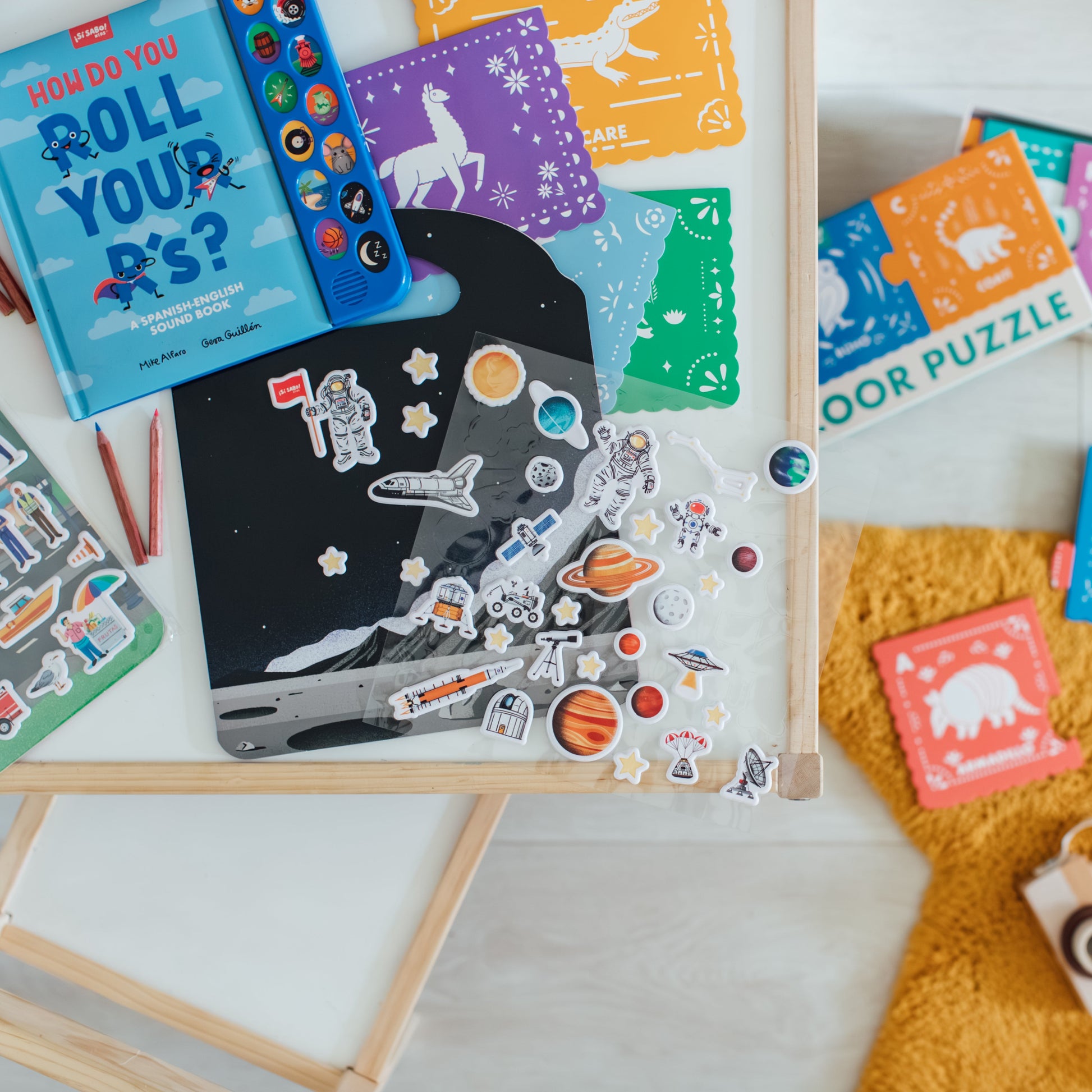 a collection of Si Sabo Kids games, puzzles, and books on a table with stickers.
