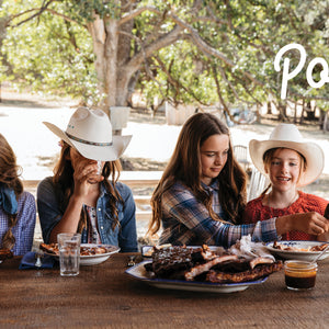 Five Marys Ranch Raised' with Four people sitting at a table outdoors, enjoying a meal with 'Pork' branding.
