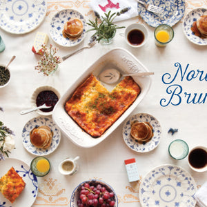 From the book 'Scandinavian Gatherings' Nordic Brunch spread with various dishes and drinks on a white tablecloth.
