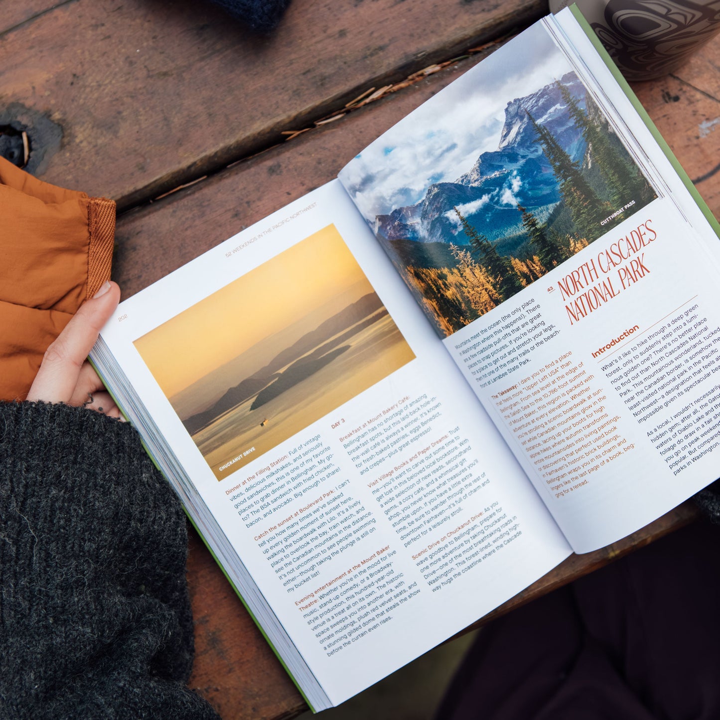 Open book with scenic photographs on a wooden surface