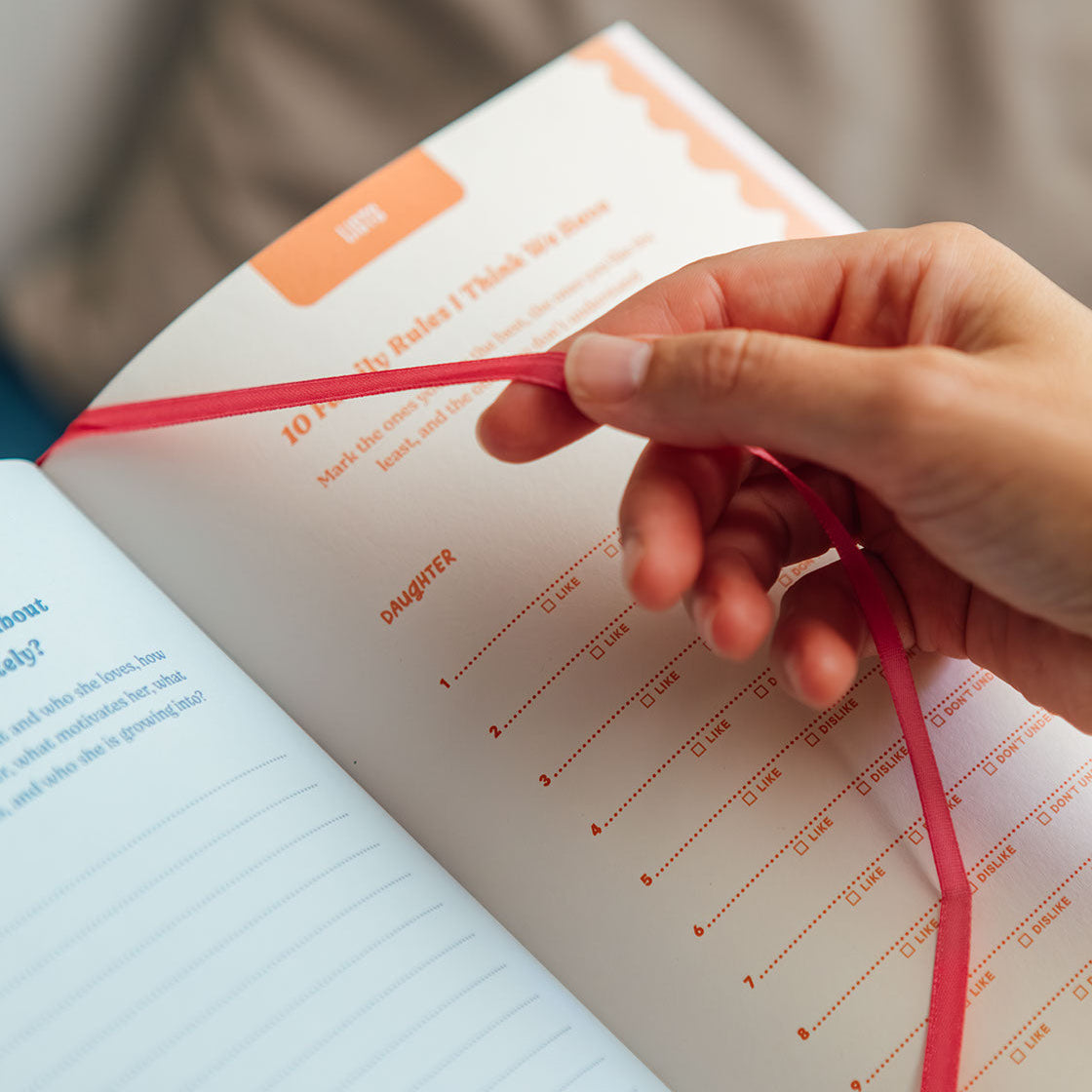 Hand holding a red string over an open book with text and a visible brand logo.