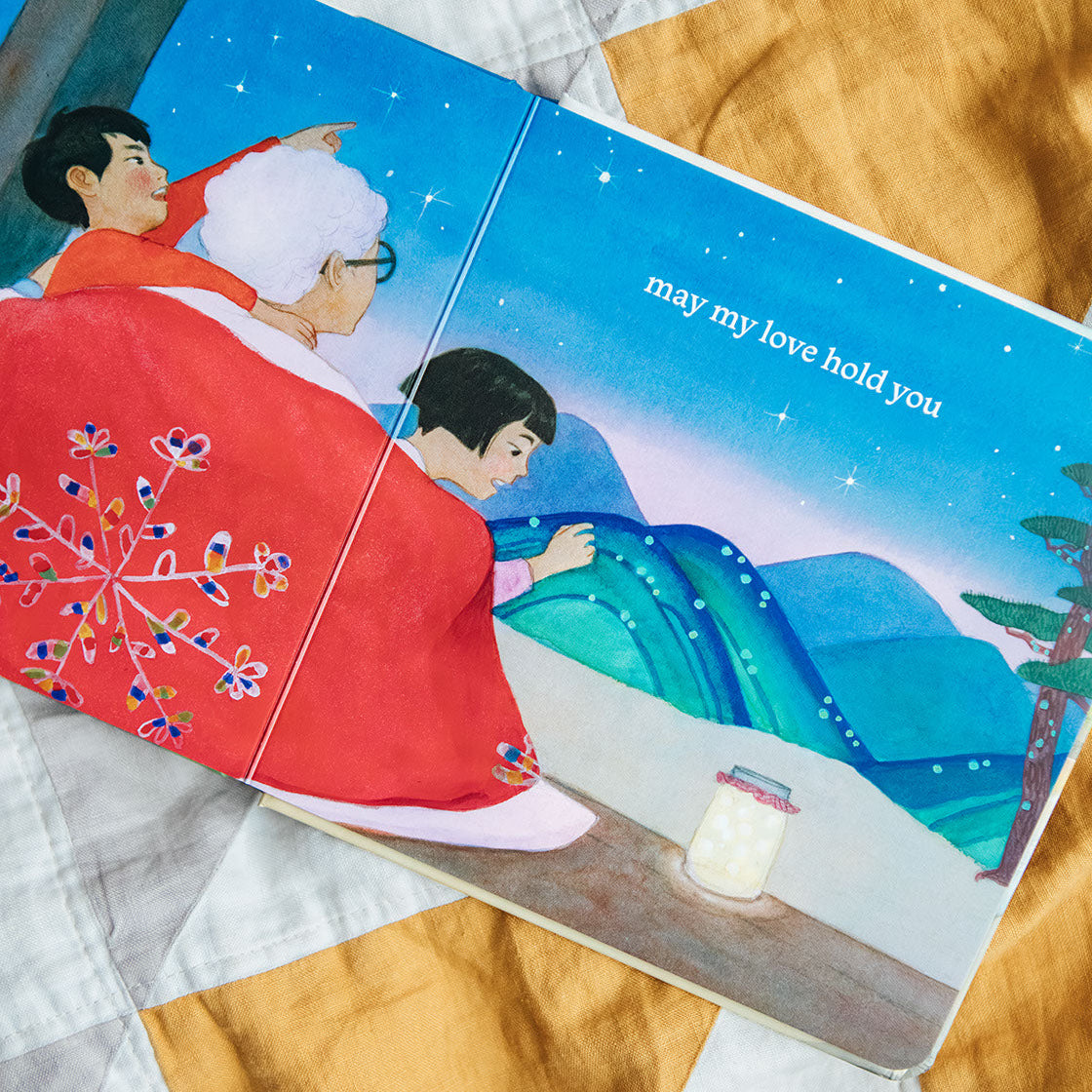 Illustrated book open to a page with two characters on a quilted surface