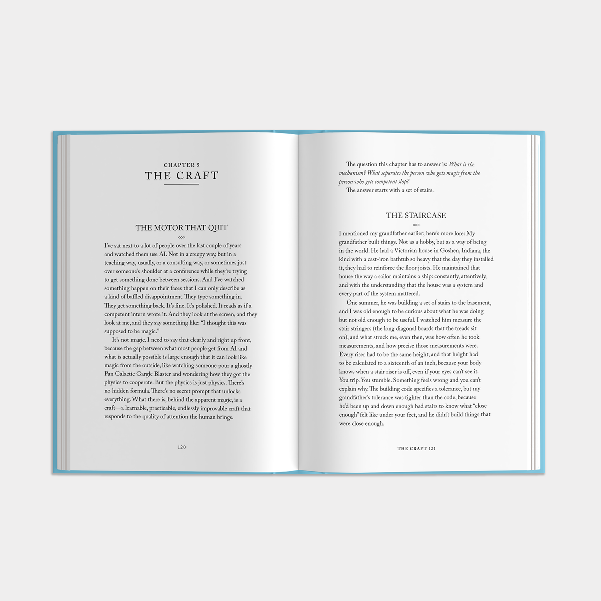An open book with two pages spread out, showing printed text and chapter titles including 'Chapter 1 The Craft' and 'The Staircase.' The book has a light blue border around the pages and is photographed against a plain light gray background.