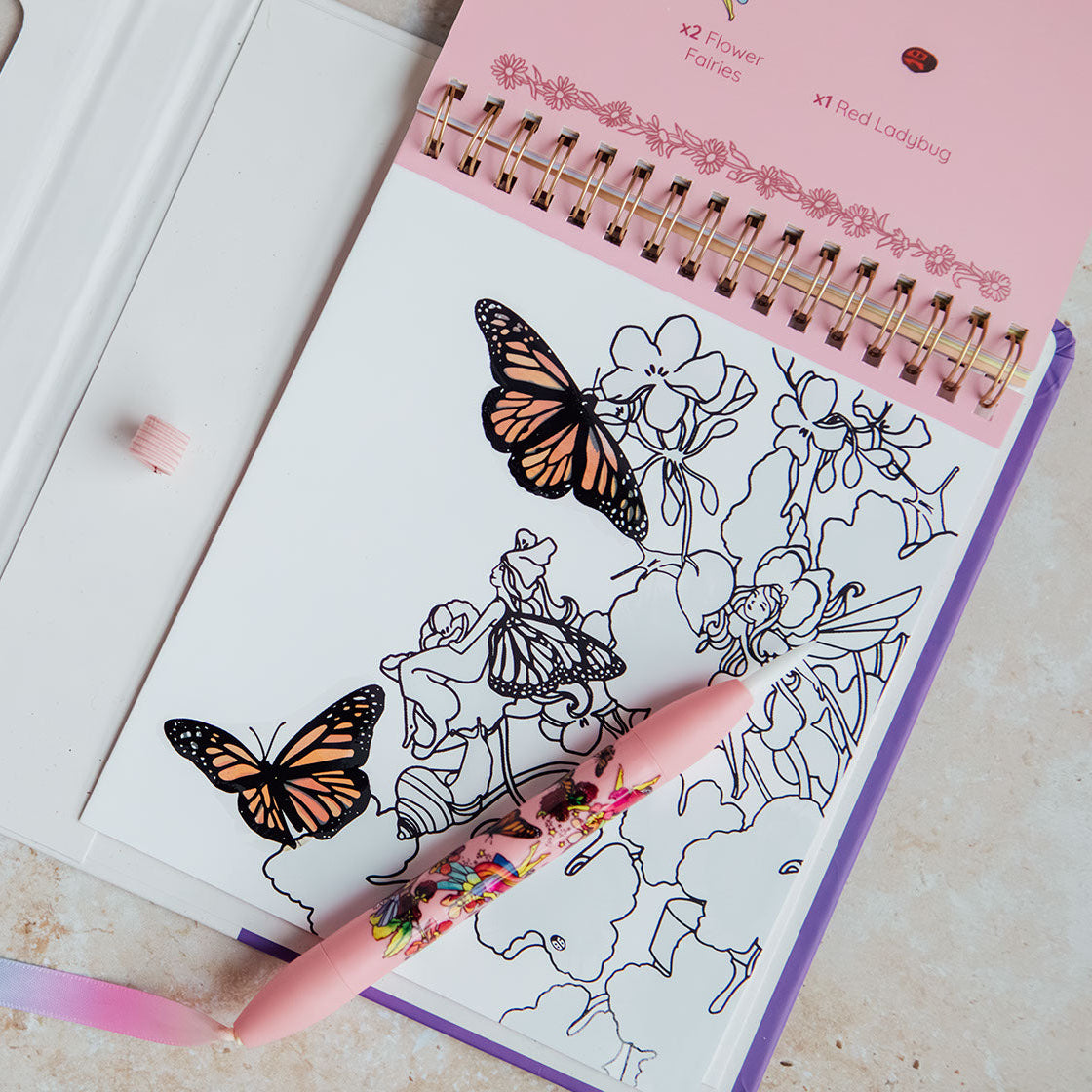 Coloring book with butterfly and fairy designs on a table