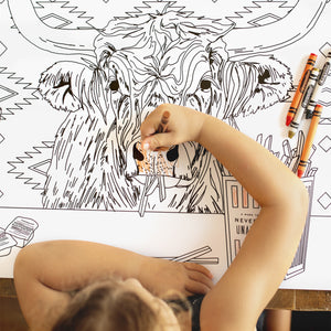 Child coloring a large animal illustration on a coloring book with crayons.