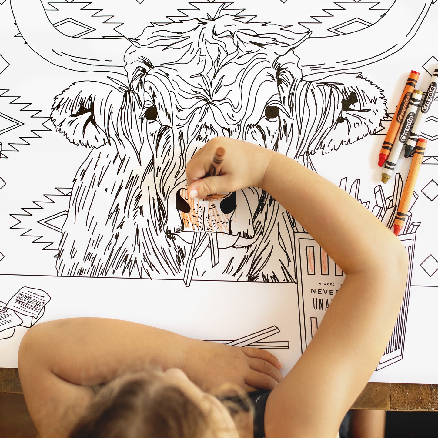 Child coloring a large animal illustration on a coloring book with crayons.