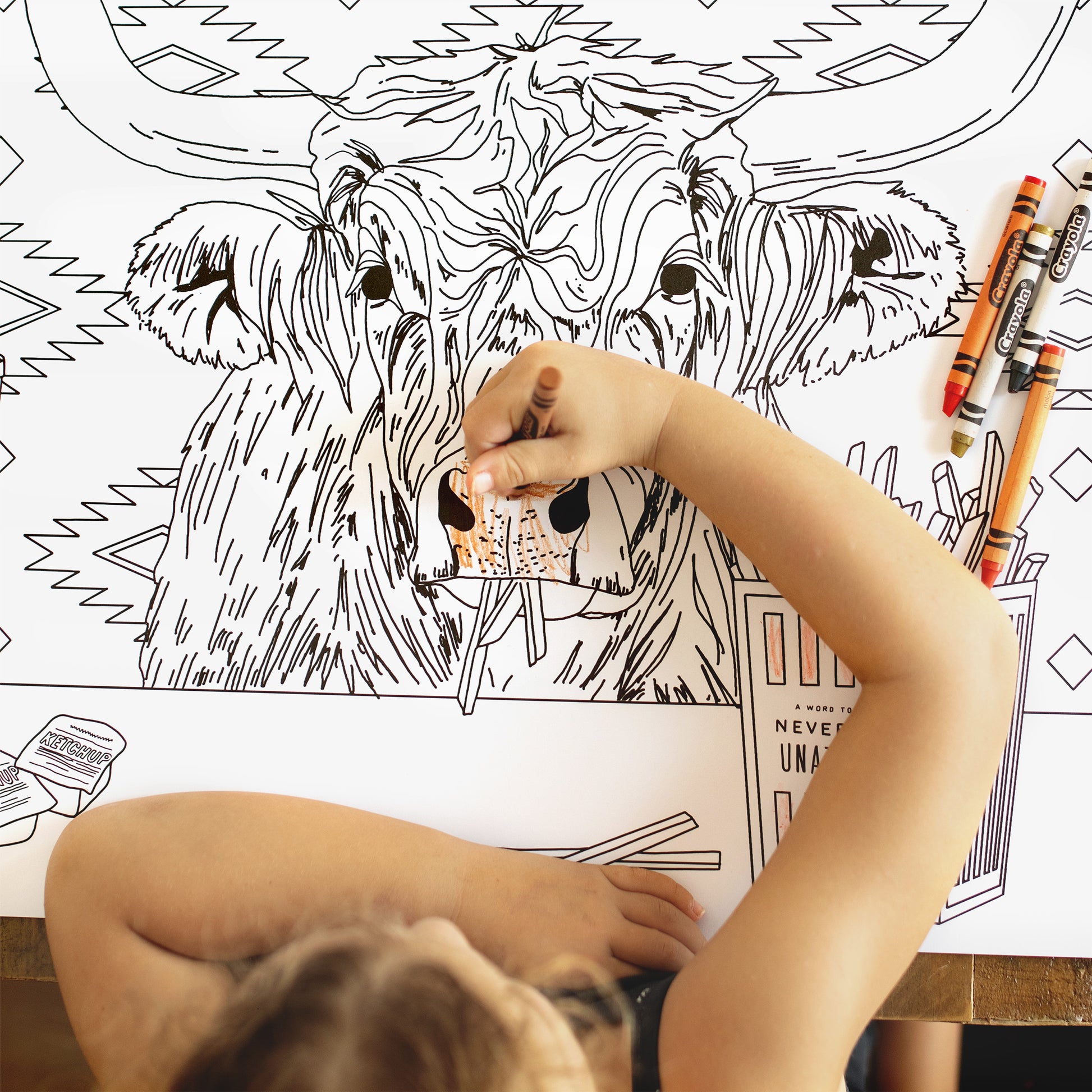 Child coloring a large animal illustration on a coloring book with crayons.