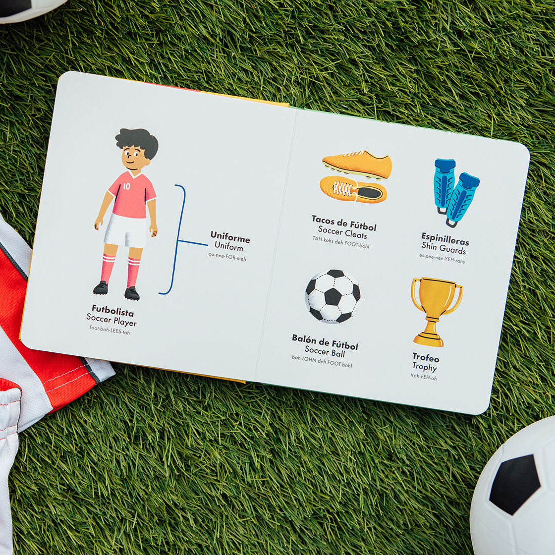 Children's educational board with soccer-themed illustrations on grass with sports equipment.
