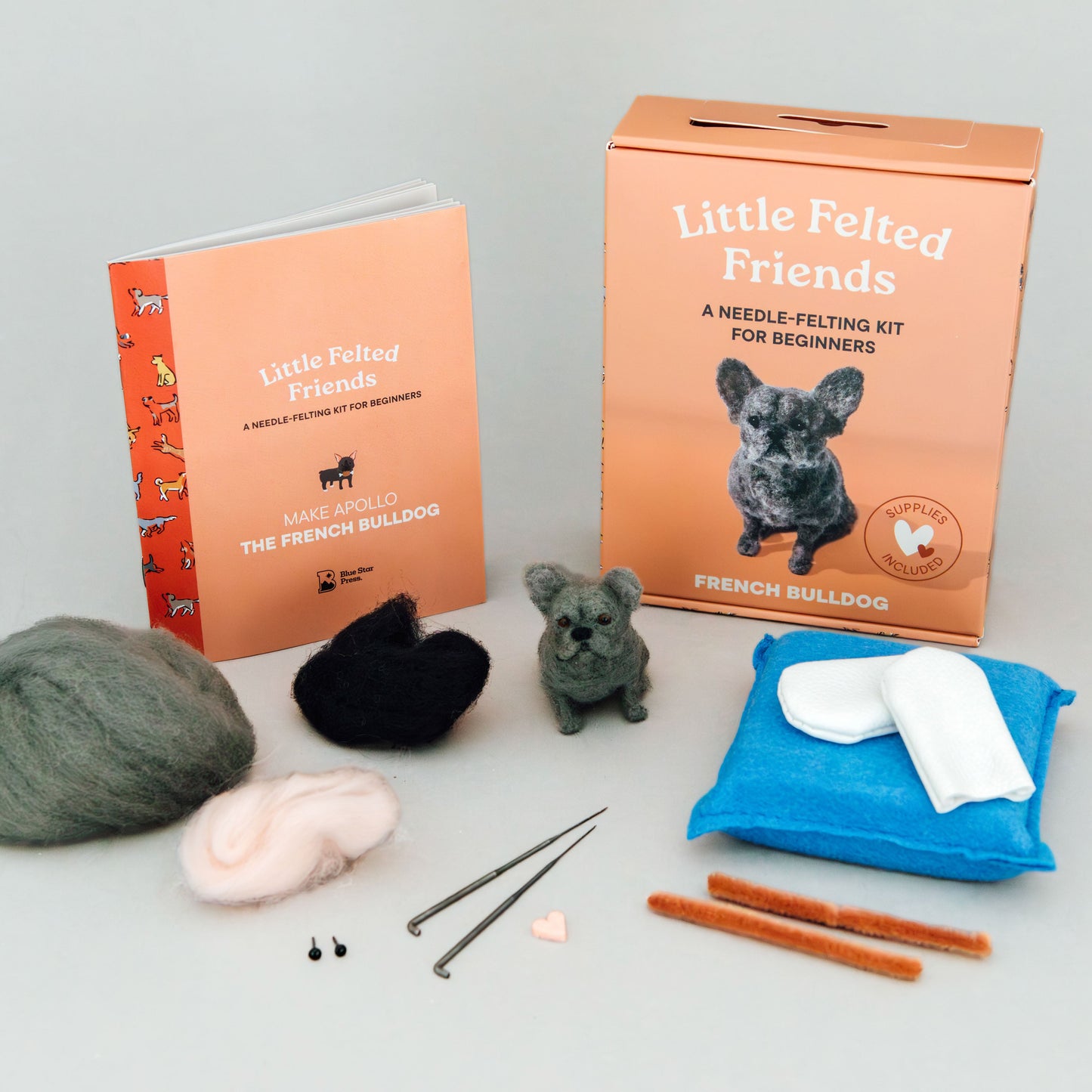 Needle felting kit with materials and packaging on a gray background